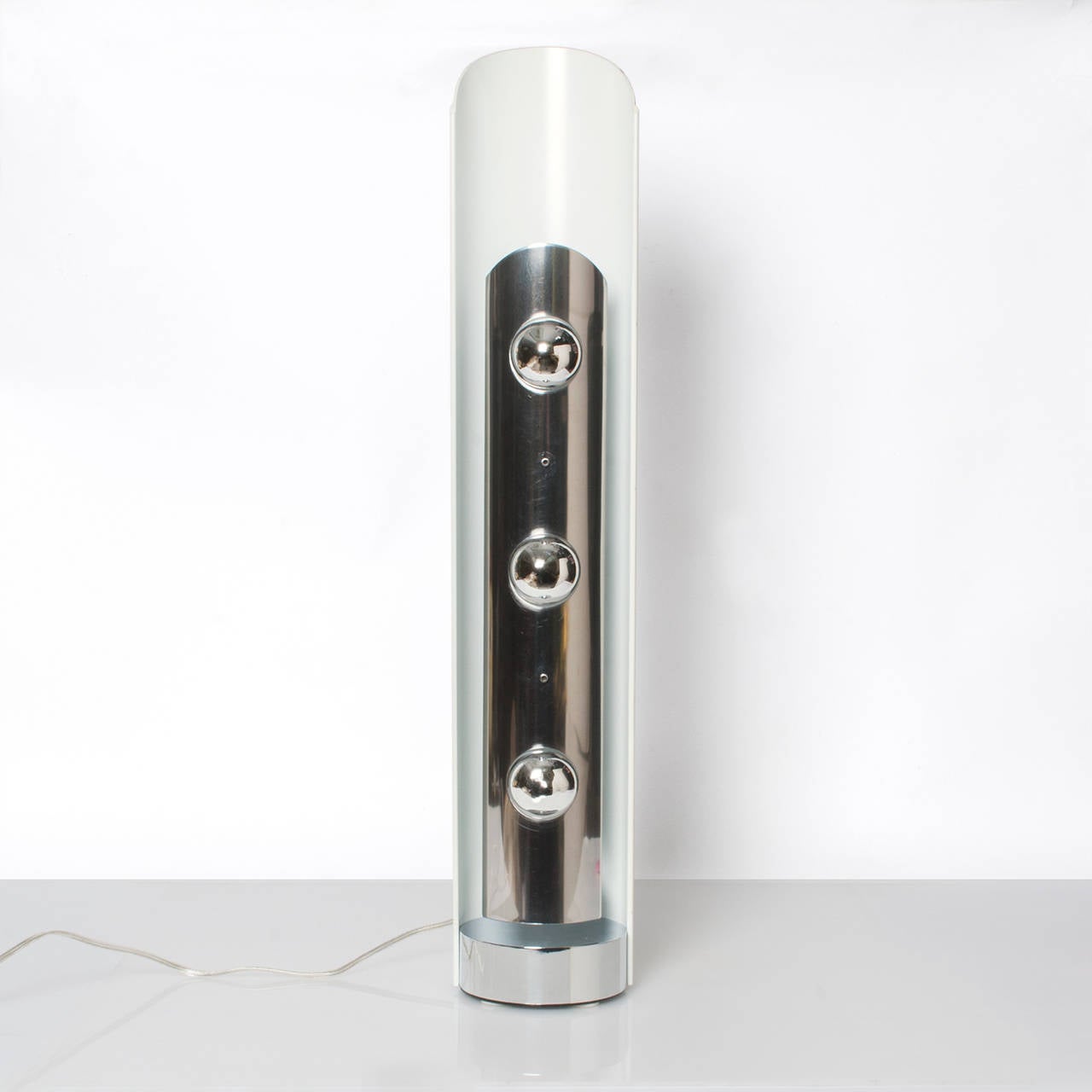 European (probably Italian) 3 light cylindrical table / floor lamp with chrome, polished steel and lacquered metal. The lamp uses 3 half chromed bulbs which reflect light into the white curved back. In the style of Arredoluce or Stilnovo but origin