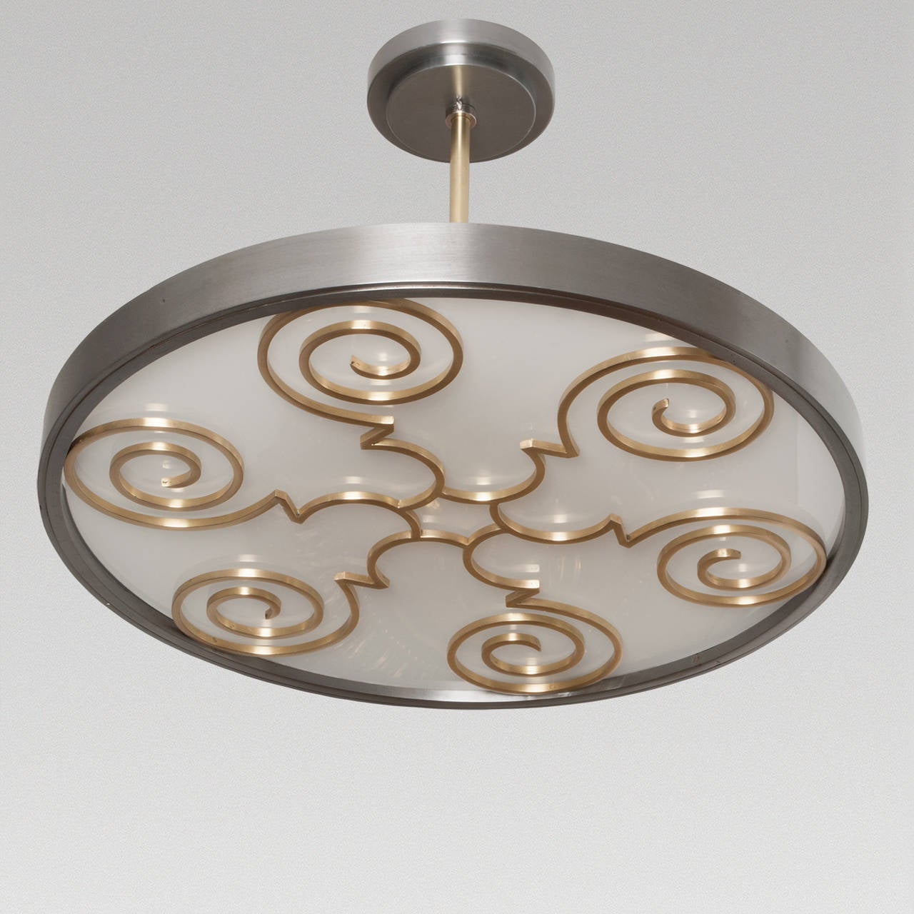 Swedish Art Deco ceiling fixture by Lars Holmstrom a co-founder and member of the Arvika Konsthantverk. This fixture has a body of polished steel with a decorative grille of polished brass. A white glass diffuser covers three-light sockets. The