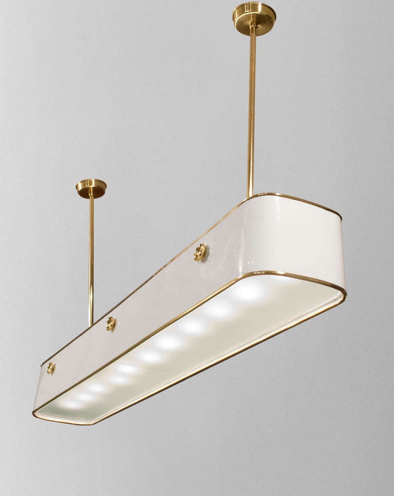 Large Swedish modernist pendant with white lacquered metal frame trimmed and detailed with polished and lacquered brass. There are 2 pierced rows which emit light when the fixture is lit. The bottom has 2 sandblasted plates of glass and there are 11