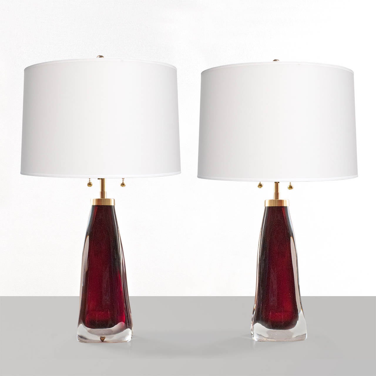 Pair of mid-century deep red cased glass table lamps designed by Carl Fagerlund for Orrefors, Sweden. Newly re-wired with high end double socket clusters in polished brass. Height: 24.5