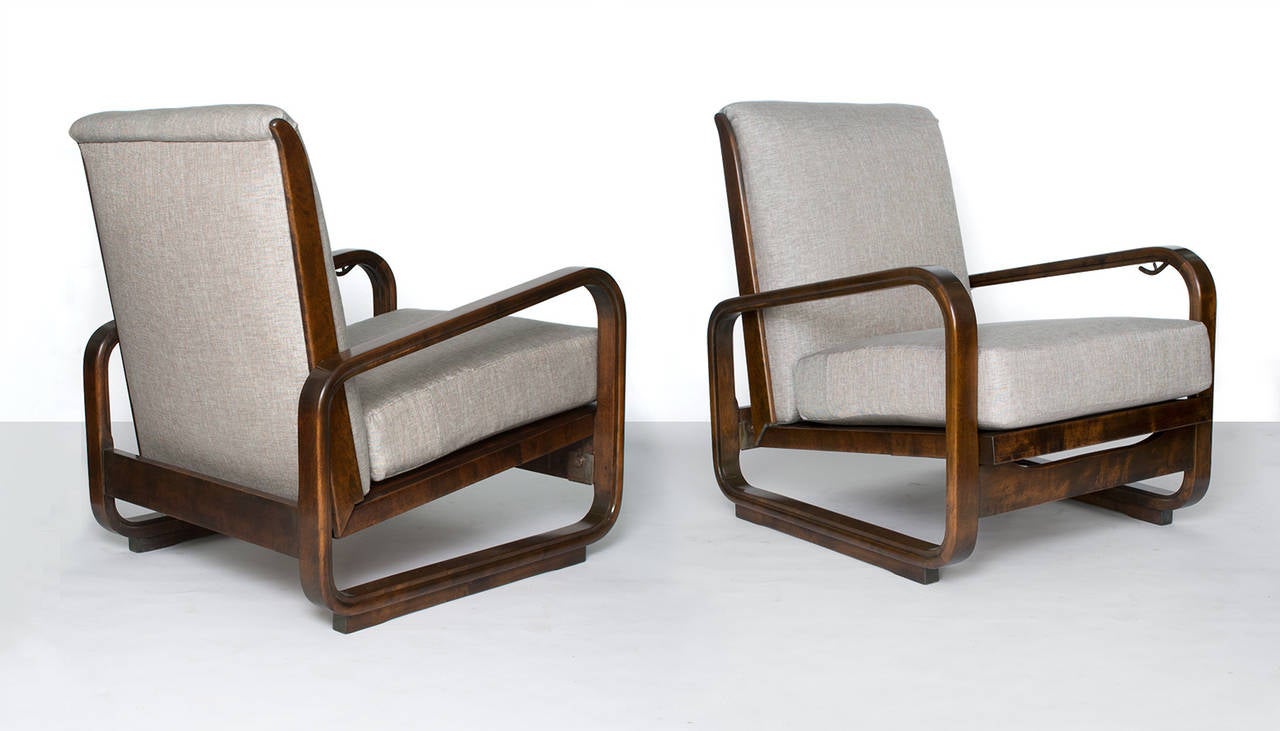 Pair of Swedish Art Deco modernist lounge chairs in stained solid birch. The chair's seat cantilever in the back and may be adjusted by releasing a discreet mechanism under the left arm. The carved arms form a trapezoid shape and rest upon a