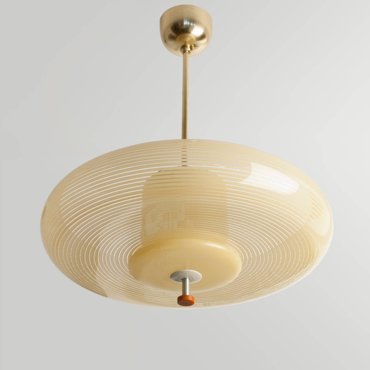 Swedish art deco pendant with clear and yellow striped glass with newly polished and lacquered brass stem and canopy. The finial consist of a polished and lacquered metal pieces and and orange bakelite disk. The lamp has been rewired and has a