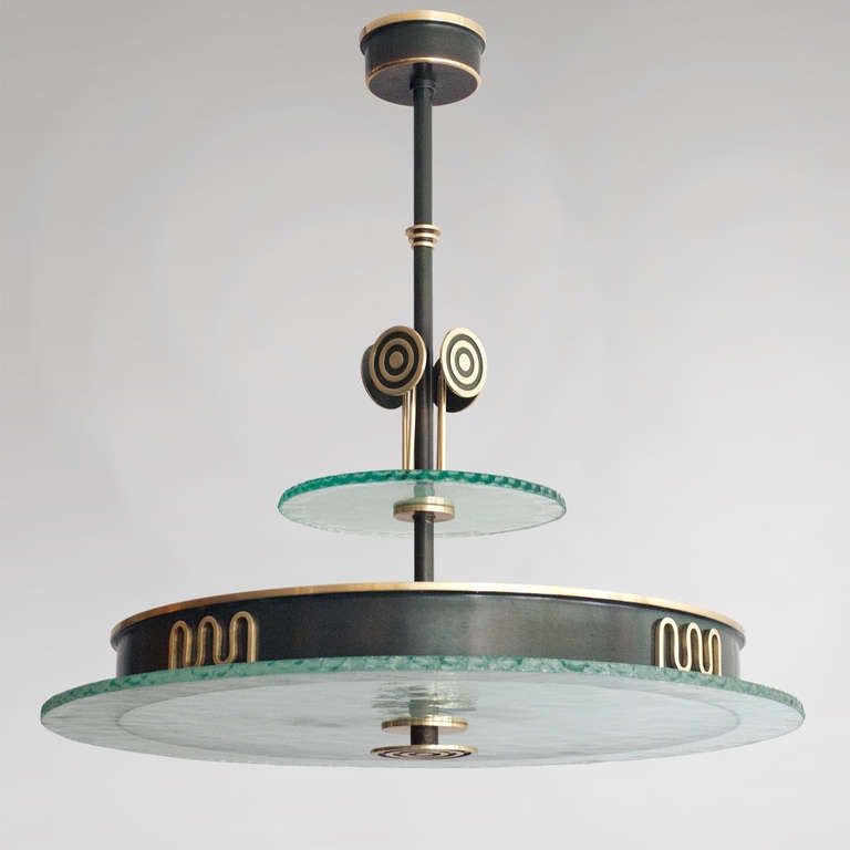 Swedish art deco patinated brass chandelier with polished brass details, made by Bohlmarks. Above the acid etch glass diffuser a stylized meander motif decorates the metal ring shade. A cluster of 4 modernist 