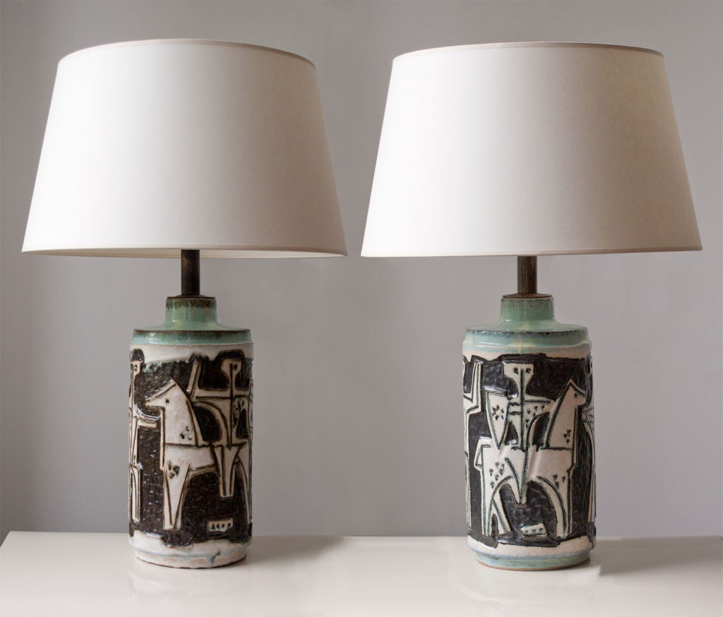 Big fabulous pair of mid-century ceramic table lamps depicting abstract figures on horses with shields. Lamps are unique hand built, richly glazed in creamy white, brown, light yellows and greens. Made by the famous Hungarian ceramics company