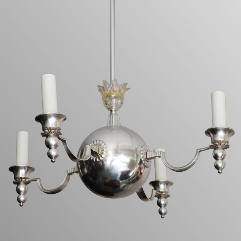 Swedish Art Deco 4-arm chandelier with a large center sphere and four reverse arched arms. The chandelier is decorated with classical stylized rosettes, a glass crown on the stem and a painted scallop edged canopy. The chandelier is silver plated