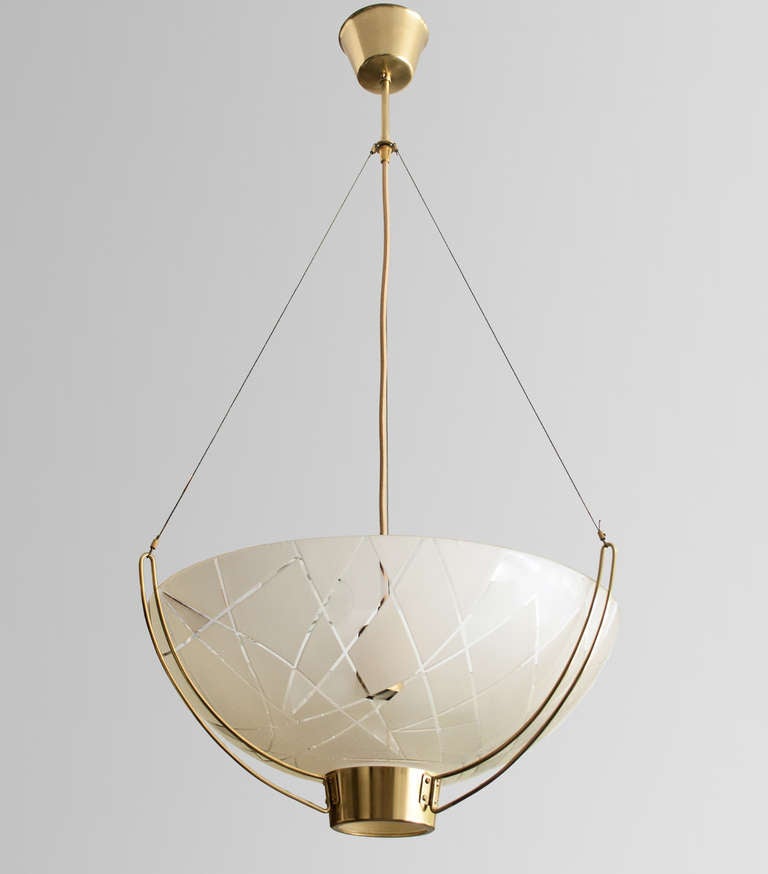 Scandinavian modern pendant with a hand etched abstract design on acid etched glass shade which is suspended by a polished brass armature consisting of three arms. The fixture is attached to its canopy by adjustable wires. Designed by Bo Notini for