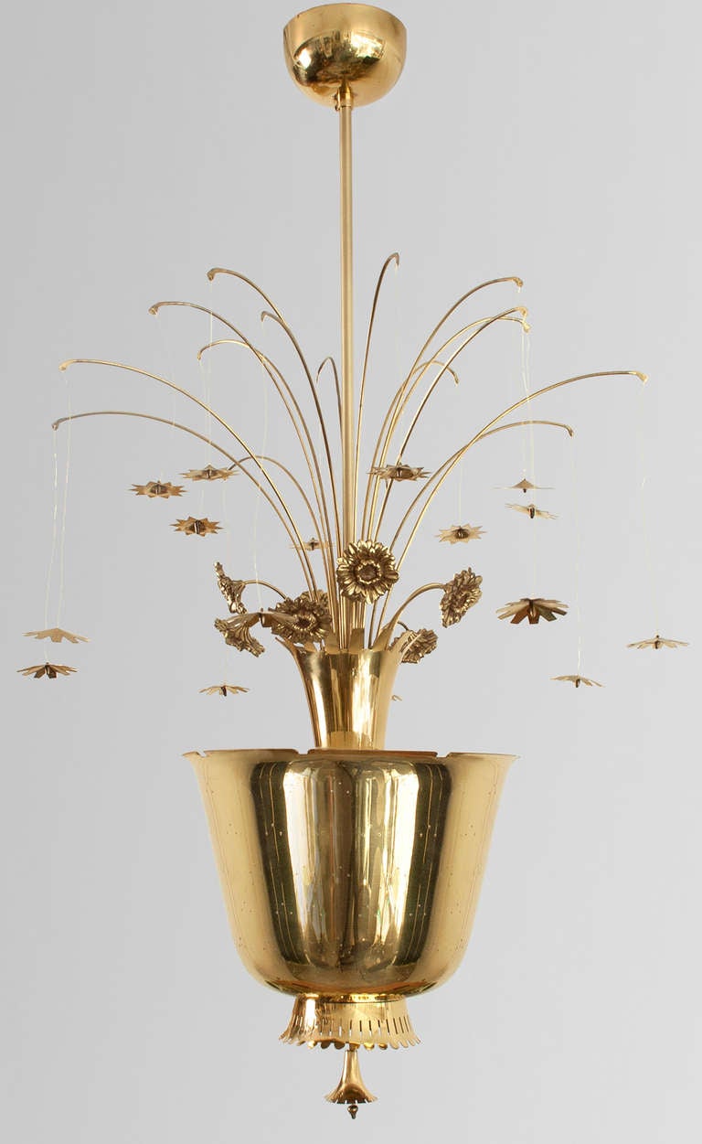 Paavo Tynell attributed chandelier with cast and formed brass flowers emerging from a center urn shaped form which houses 3 light sockets. The urn is pierced with a pattern of 3 holes which release light when this fixture is lit. There are 16 arms