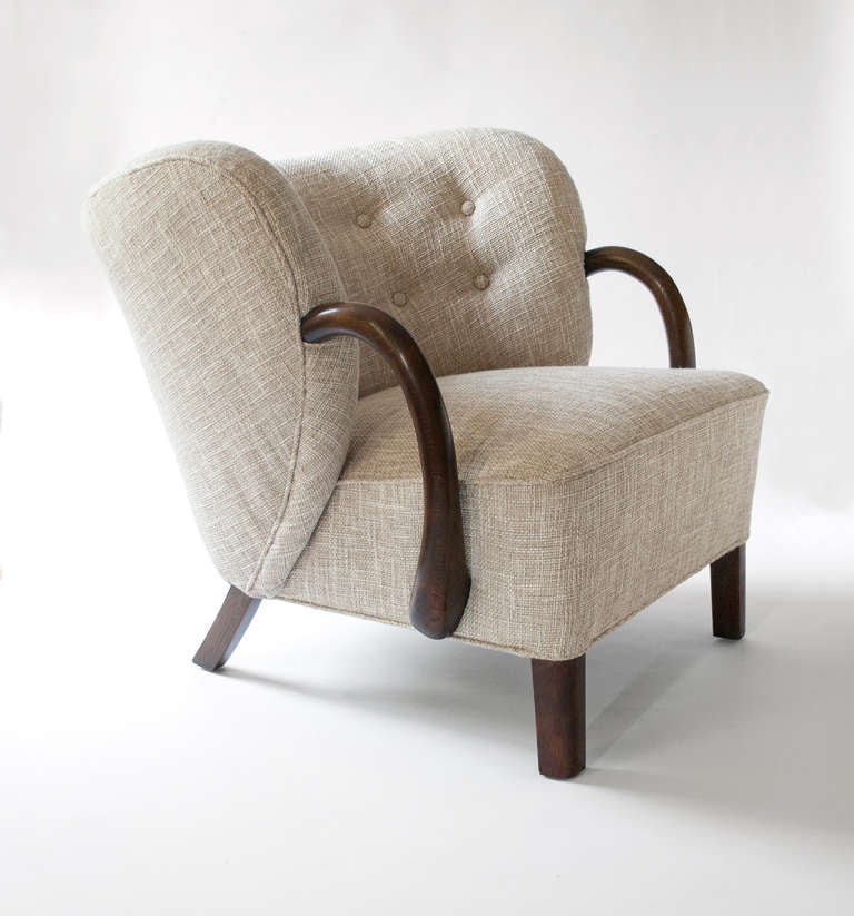 Danish art deco upholstered armchair with a dramatic curved form. Solid carved arms and legs are walnut stained oak. In the manner of Viggo Boesen, circa 1936-1940. Newly upholstered and refinished. Height: 28