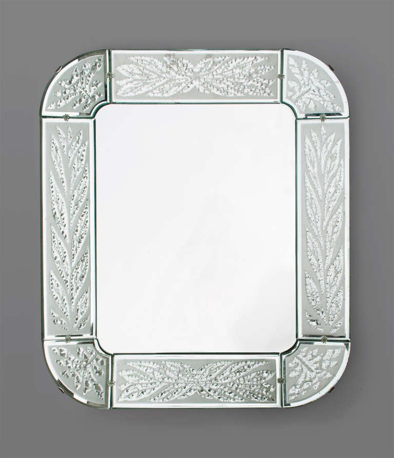A beautifully detailed Swedish Art Deco mirror with an acid and hand etch frame. Each of the 8 frame elements has stylized leaf designs which are raised against an acid etched mirror glass piece. The mirror is mounted on a solid elm wood frame with
