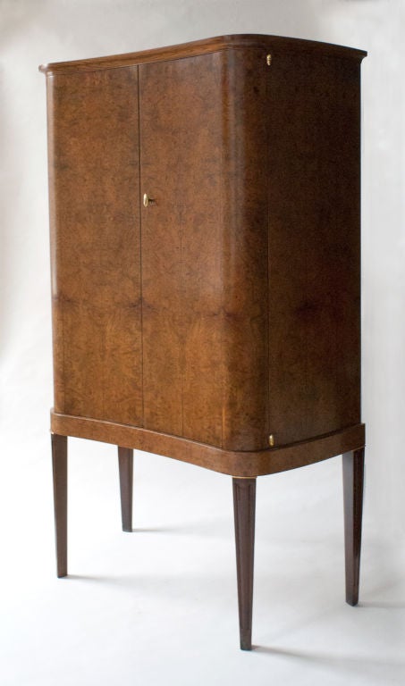 Elegant mid-centruy Swedish 2-door cabinet with serpentine shape. Veneered with columns of carpathian elm. Inside are 3 adjustable shelves and 2 drawers at the bottom. Polsihed brass key, hinges and details. H: 55