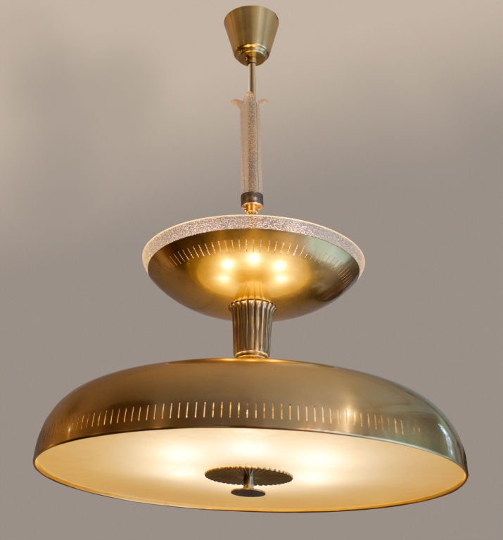 A rare and large Swedish Art Deco polished brass and glass chandelier made by Bohlmarks. The bottom domed section houses 6 standard base sockets behind a large acid etched glass disk with brass and steel finial. The upper shade has 3 additional