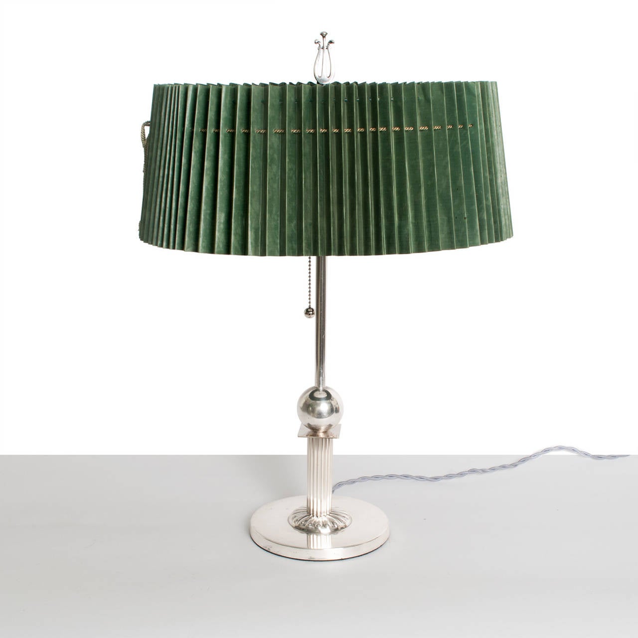 A refined Swedish art deco silver and silver plated table lamp with original oval shaped pleated paper shade. The lamp features a fluted column which supports a solid silver rectangle and hollow sphere. The base is simple disk with a rosette