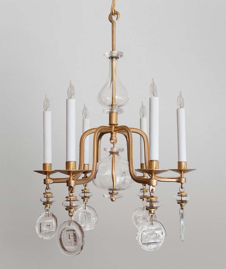 Swedish mid-century 6-arm chandelier in gilded wrought iron by Erik Hoglund. Each arm is detailed with a hanging crystal with either a fish or a man's face. A large clear crystal finial hangs in the chandeliers center. Newly electrified for
