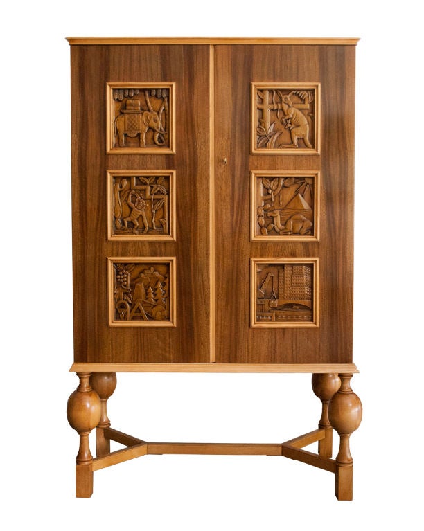 Fine Swedish Art Deco 2-door cabinet with 6 carved inserted panels. Hand carved panels depict various animals and landscapes. Cabinet's base consist of 4 ovoid balusters and a 5-piece stretcher. There are 2 adjustable shelves and 2 stationary