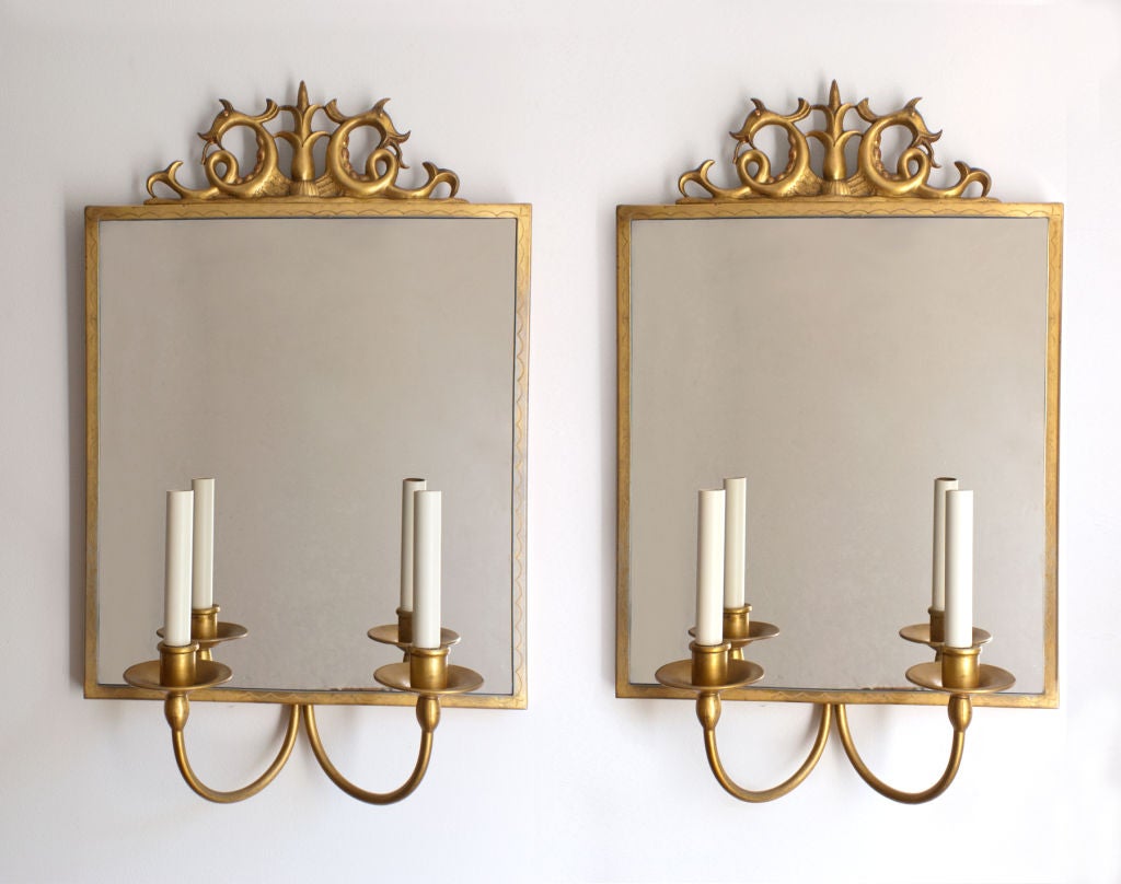 A rare pair of Swedish Art Deco 2-arm mirror sconces designed by Gustav Bergstrom. Frames are gilt over pewter and Incised with a serpentine pattern.<br />
The frame tops are decorated with a sculpture of a lotus flower flanked by 2 mythical sea