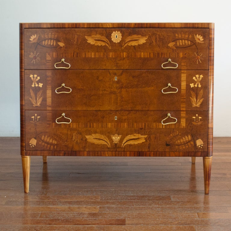 Elegant Swedish art deco chest of drawers with exquisite floral marquetry design. The original drawer pulls are solid polished brass and have a gentle curved form. The chest's top has a rectangular inlay design with marquetry flowers. The chest has