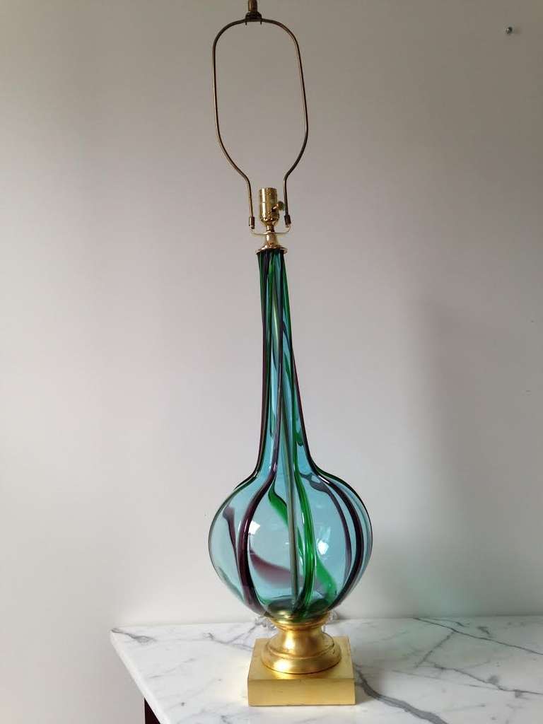 Gorgeous pair of vintage Italian Murano glass table lamps in aqua with raised
amethyst & green swirl stripes from the 1960s. The pair of lamps sit atop a gilded gold base and have been rewired with 3 way switch. Lovely pair to flank a entry console