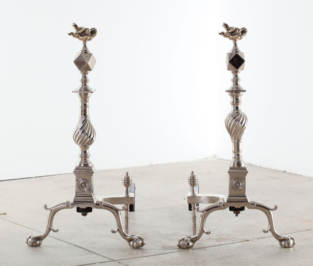 Exceptional pair of polished nickel andirons with a faceted and swirled center body topped with a stylized brass flame.