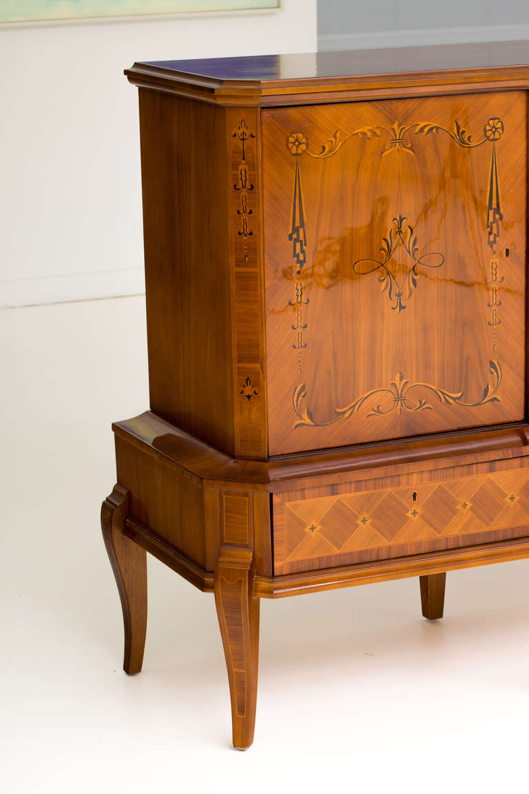 Exquisite Hungarian Art Deco walnut sideboard with exotic wood inlays consisting of ebony, lemonwood and Macassar. Sideboard features three compartments with adjustable shelves and bottle rack. Four drawers below the compartments provides ample