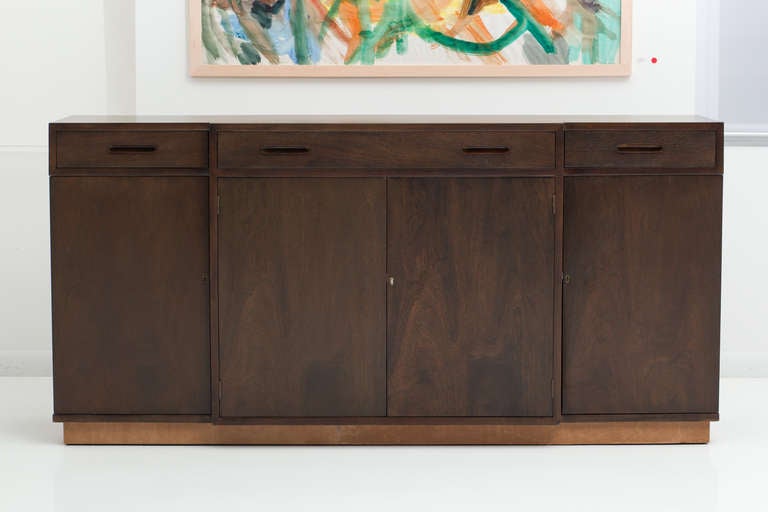 Fantastic sideboard designed by Edward Wormley features three top drawers suitable for flatware storage. The center compartment houses four drawers and each side compartment has two shelves. Each compartment has a lock. Base is wrapped in tan
