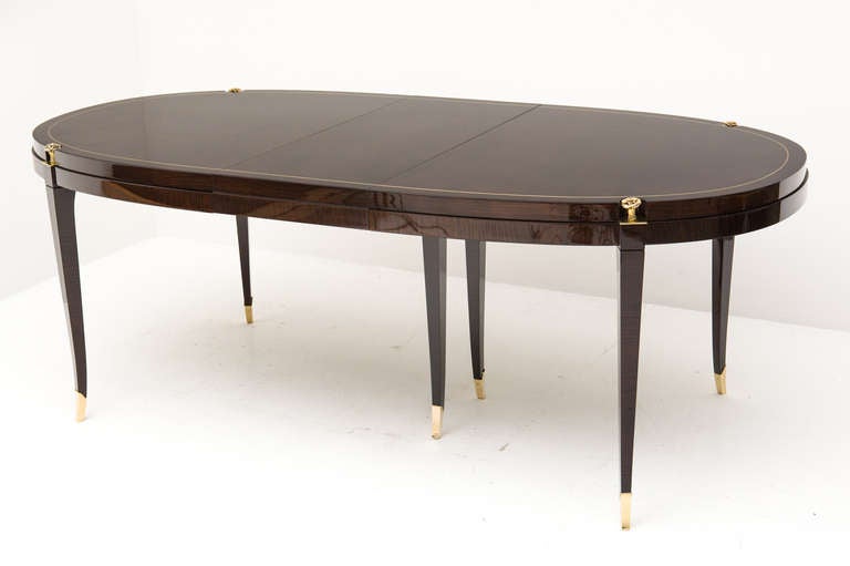 Ultra chic ebonized Palisander dining table with three leaves (two with skirt), two host chairs and six side chairs. Dining table features brass pinstripe inlay around perimeter, brass sabots and four florets. Dining chairs feature two flower buds,