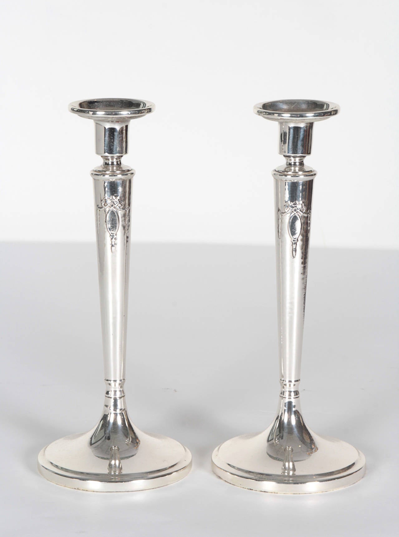 Pair of English Art Deco sterling silver candlesticks with a tied ribbon bow detail on a tapering column body. Stamped on bottom.