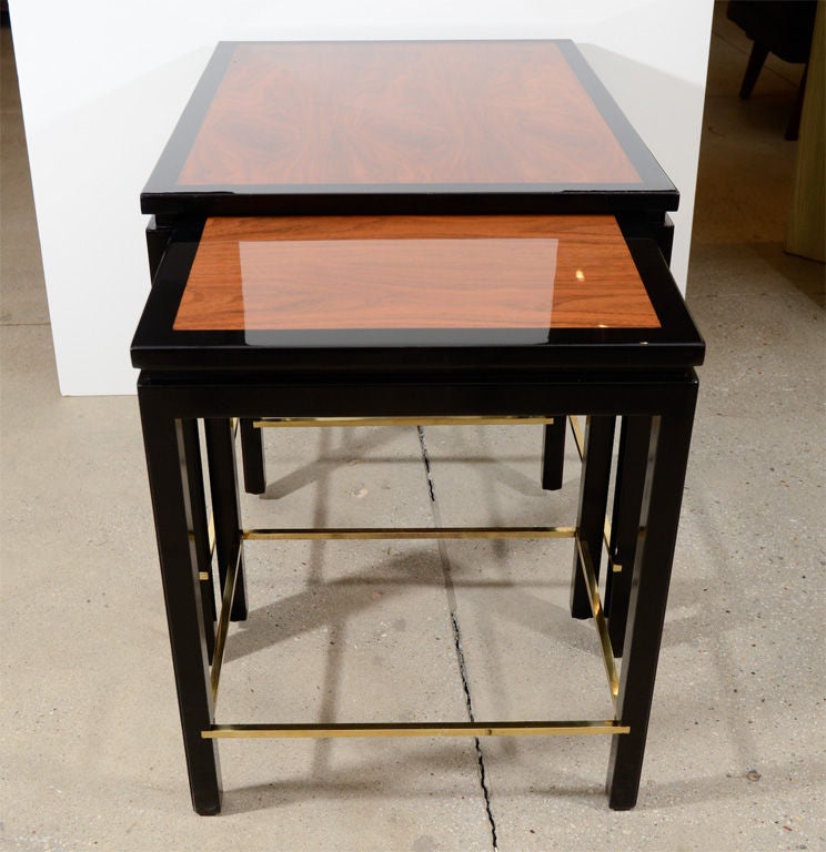 Exceptional set of three walnut nesting tables with ebonized edge and brass stretchers. The two smaller tables that nest under the main table measure 17.5