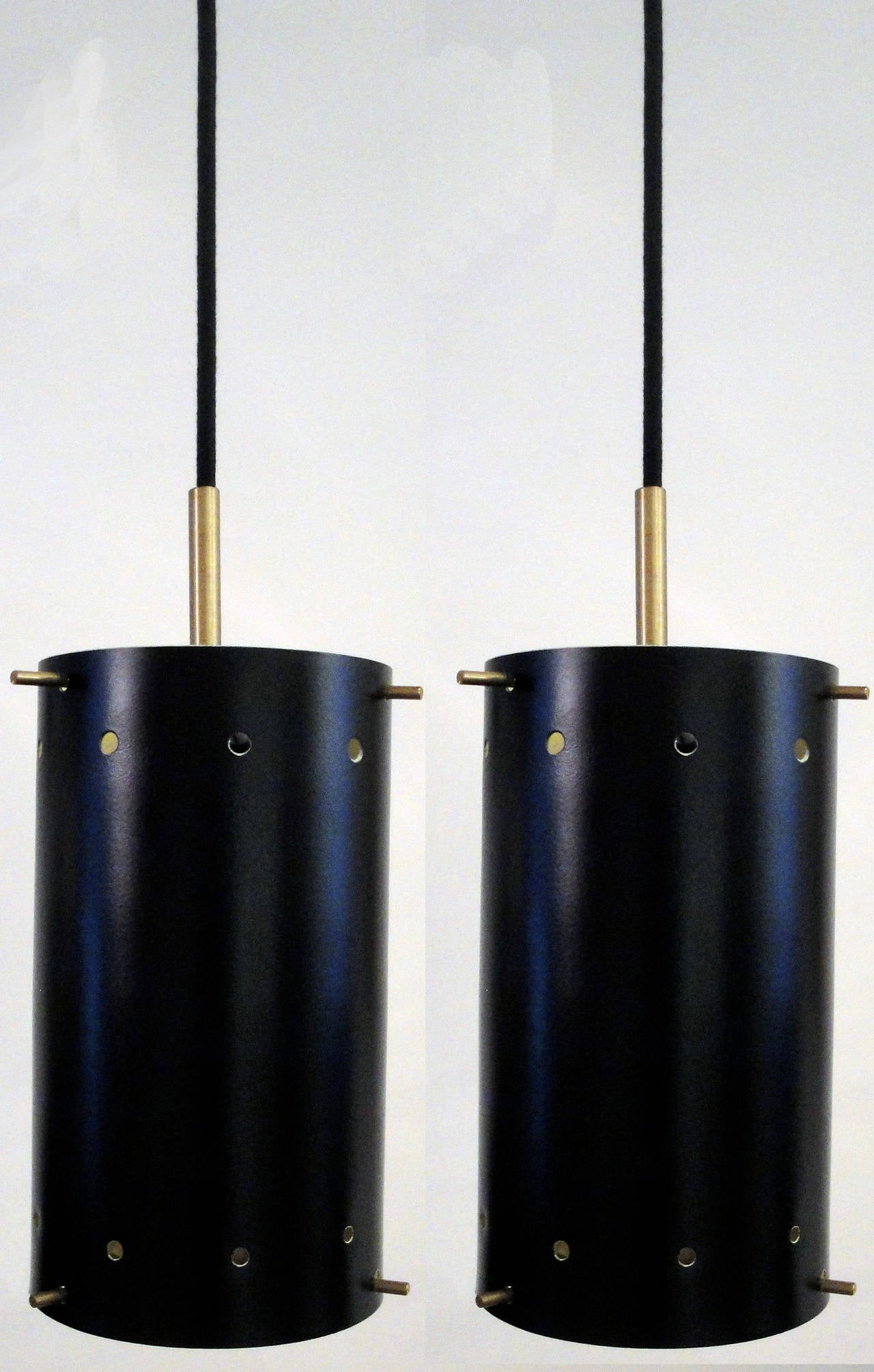 Black enameled metal shades with perforated round holes,
off-white rings at the bottom and brass fittings. The lengths can be adjusted to your needs.