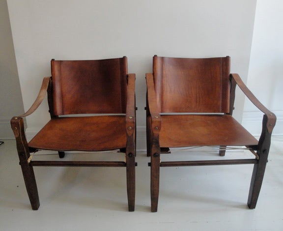 Pair of vintage American safari chairs. Wood frames with leather seats and arms.These chairs produced by 