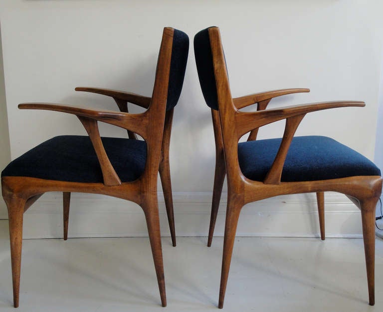 A sculptural pair of walnut armchairs designed by Carlo di Carli, restored with navy color new upholstery.