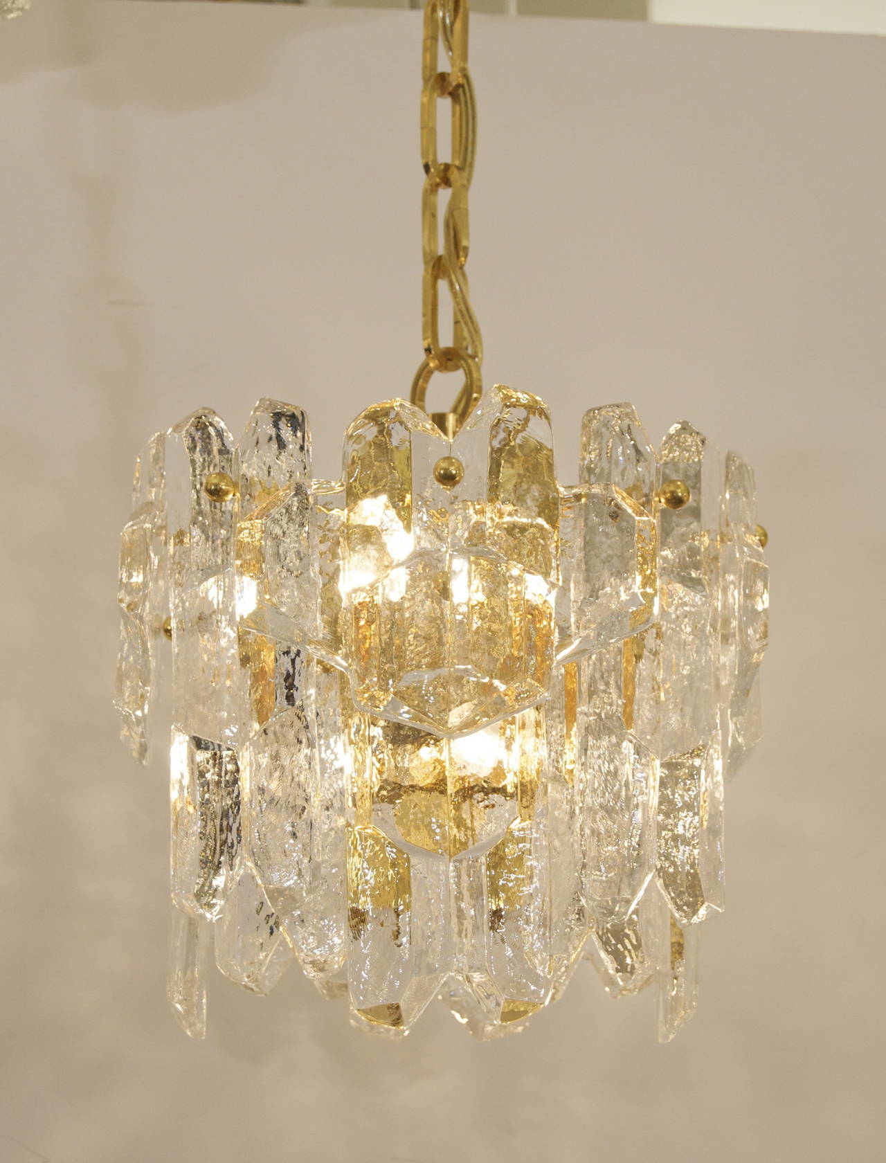 Exceptionally lustrous Kalmar ice glass chandelier, a rare pendant version with three separate patterns of glass hung from a gold-plated body. The angular structure and patterning of the glass creates a bold visual statement.

Takes eight E-14