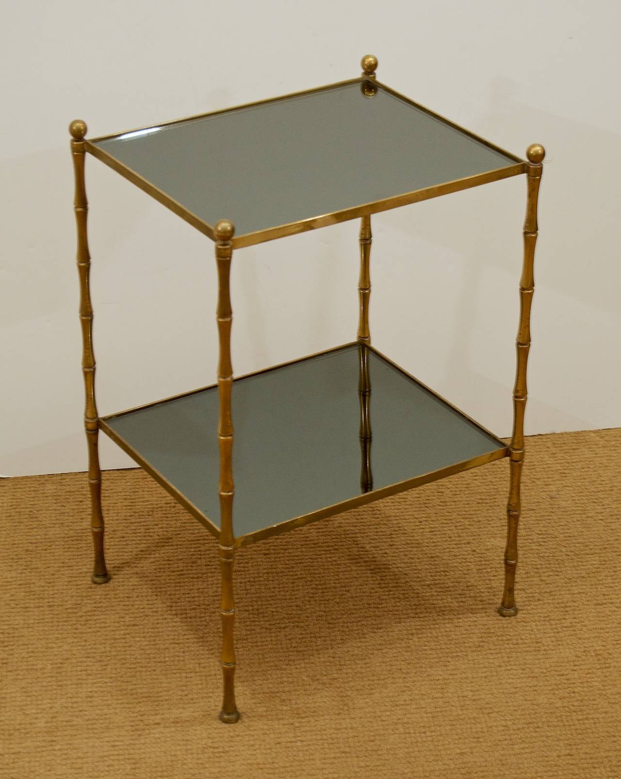 This elegant brass two-tiered table with black glass mirror has multifunctional use and elegant style to fit in all decors.