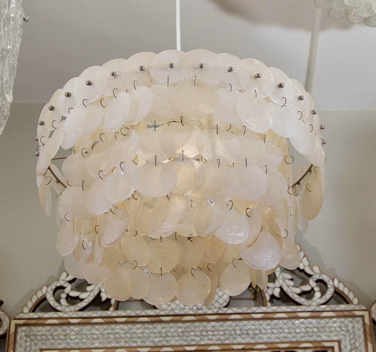 Fabulous capiz chandelier, composed of three rings of square profile stainless steel and strands of capiz shell discs. The capiz provides a particularly warm, diffused lighting effect.
 
Takes one medium based bulb up to 75 watts, new wiring.