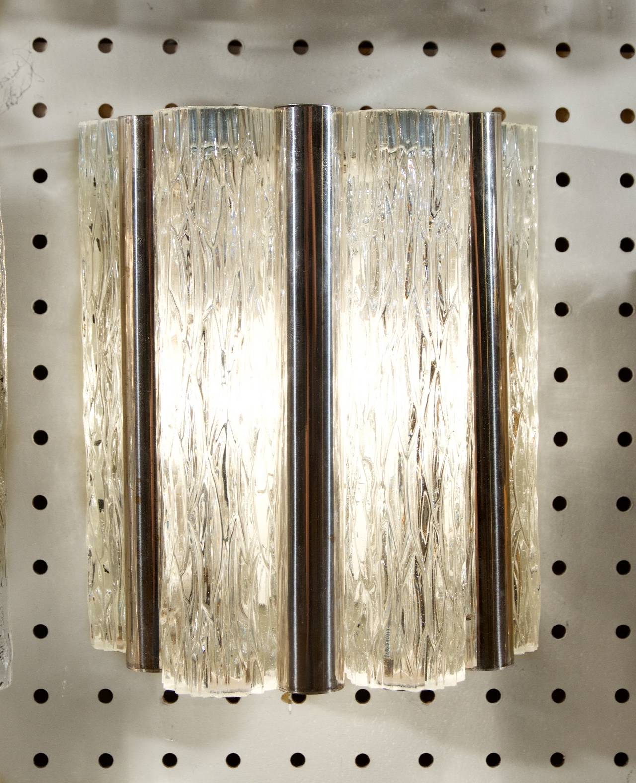 This beautiful pair of sconces cast beautiful light through clear patterned ice glass and warm silver plated tubes. 

Takes one medium base bulb, up to 75 watts. 

Price is for the pair.
