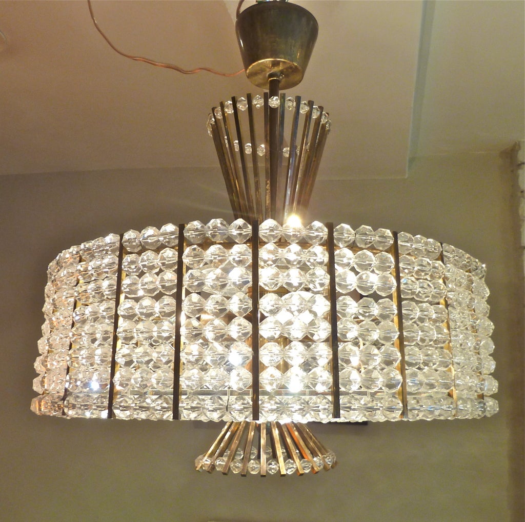 Bright and fun 1960's chandelier featuring two starbursts of brass protruding from a central drum lined in lucite beads.  Casts excellent light with 6 sockets.