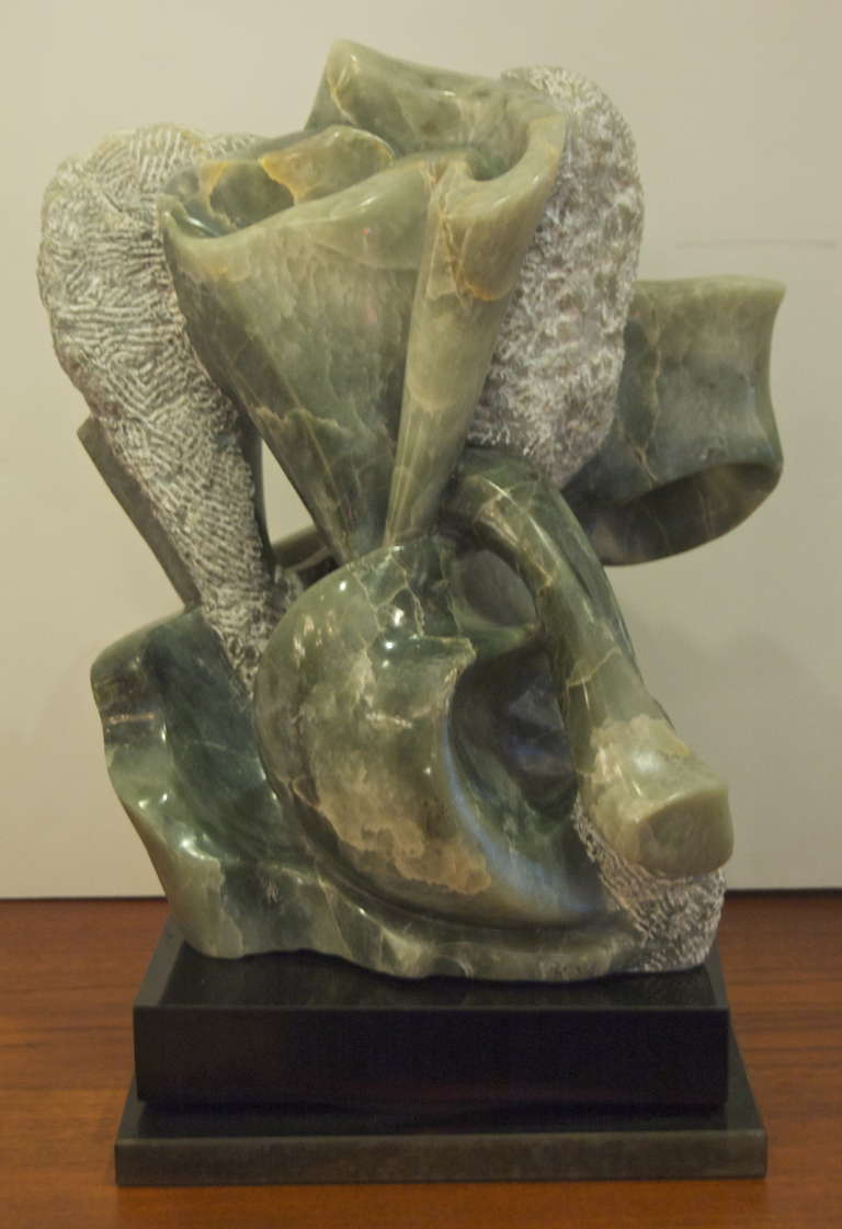 Abstract green marble sculpture with flawless design. Piece is mounted on a stone rotating surface.