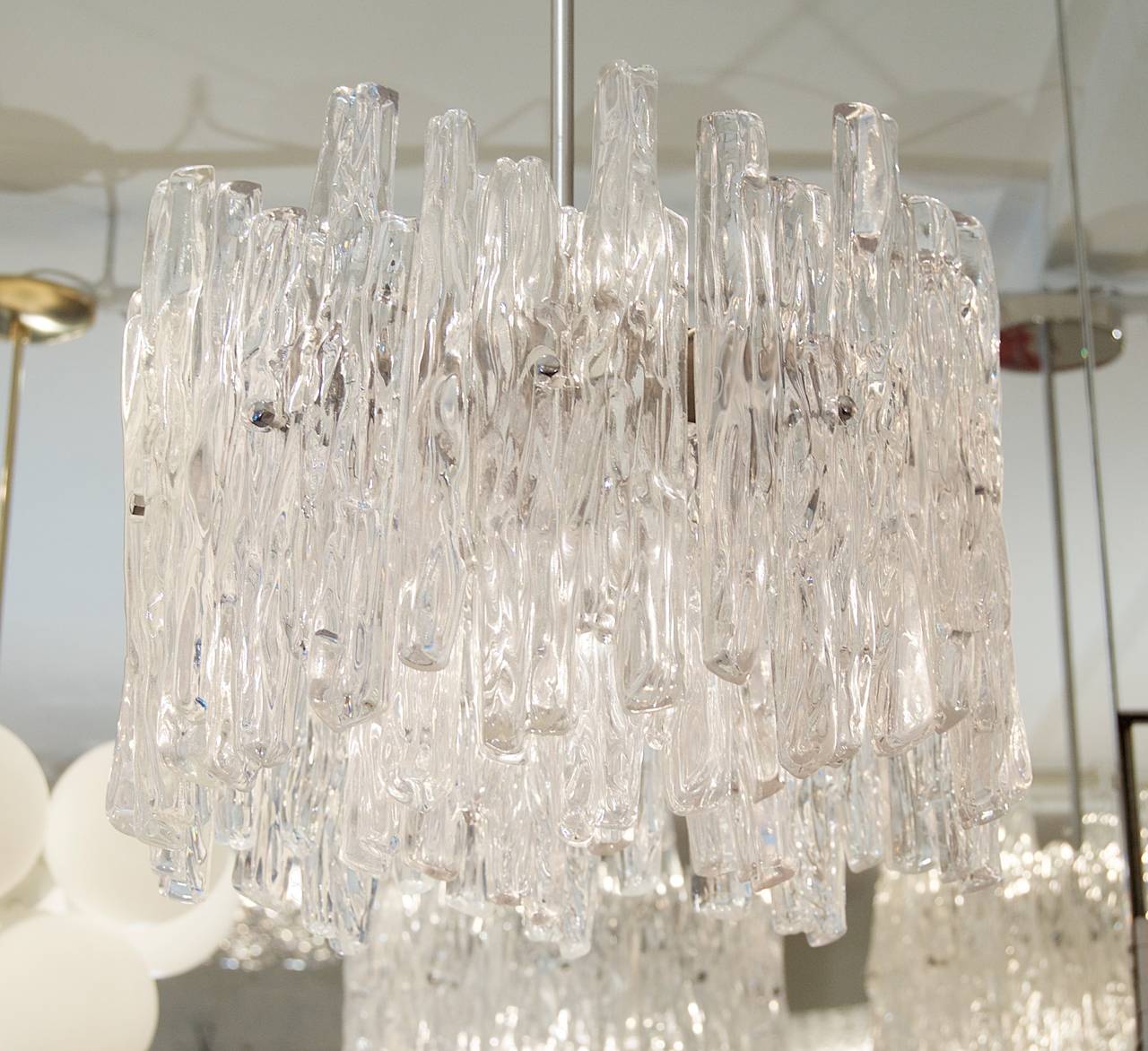 Excellent and petite chandelier in the style of Kalmar ice glass, with substantial Lucite pieces in two tiers. Some opaqueness to the Lucite. Dramatic, elegant statement piece.

Takes three E-14 base bulbs, four radiating and one downlight medium