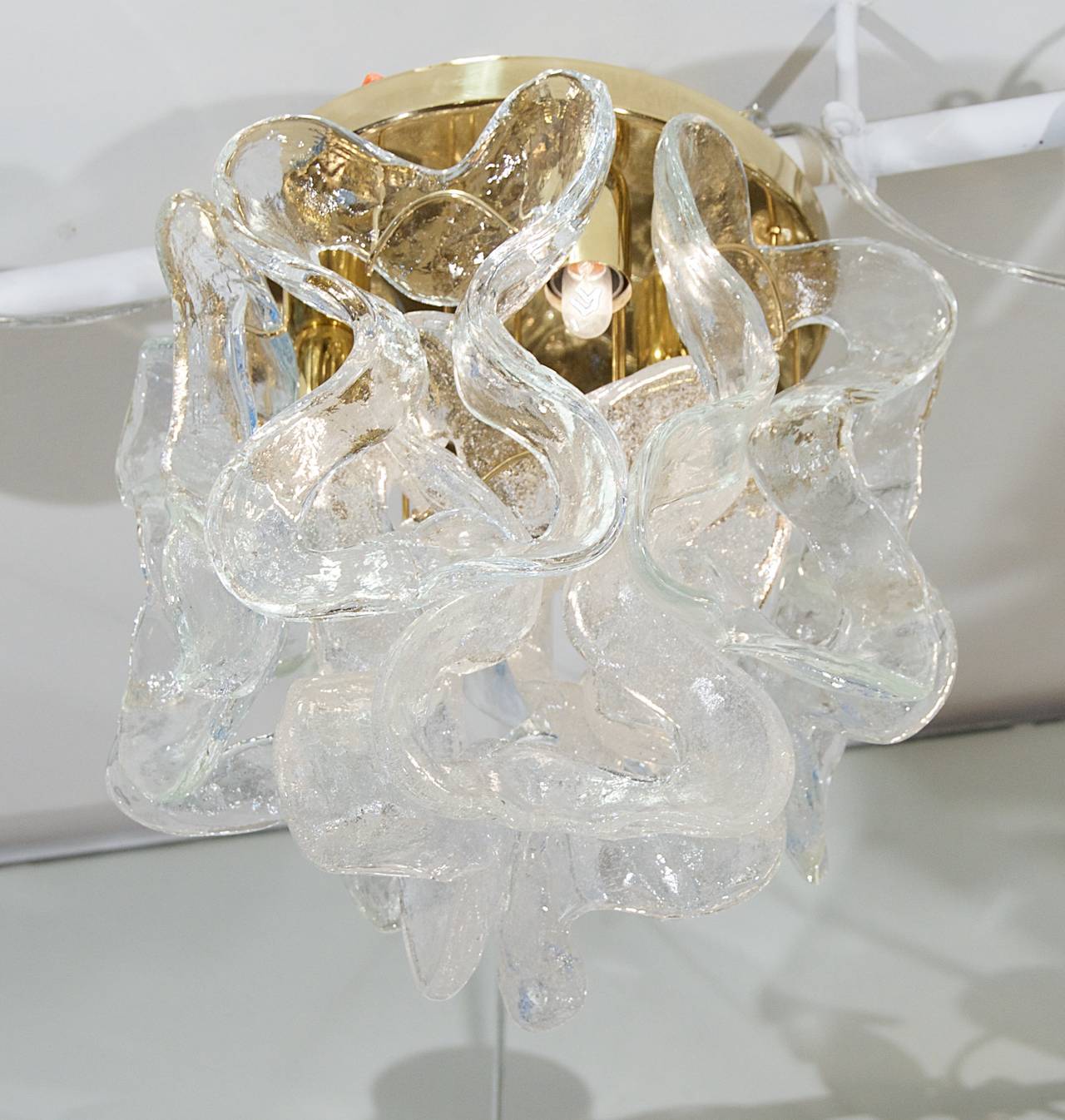 Unique organic wave patterned Kalmar flush mount chandelier with nine glass chains of alternating clear and frosted textural pieces hanging from a brass body. 

A unique and elegant statement. 

Takes three E-14 based bulbs up to 40 watts per