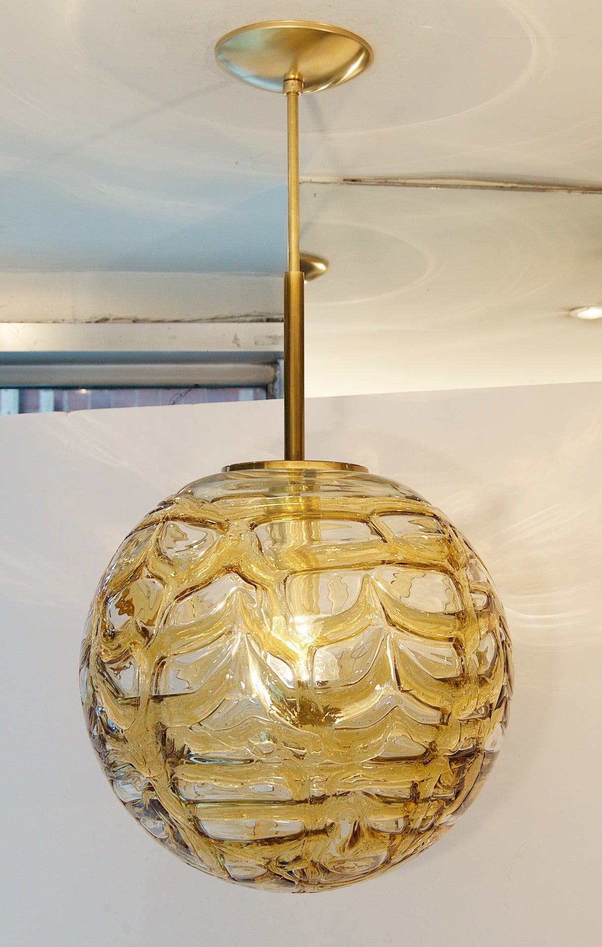 Fantastic Doria pendant will complement all decors. Heavy textured wave surface glass with amber tints infused in the waves, variegated from clear areas.

Brass hardware.

Takes a single medium base bulb up to 100 watts, new wiring. Length of