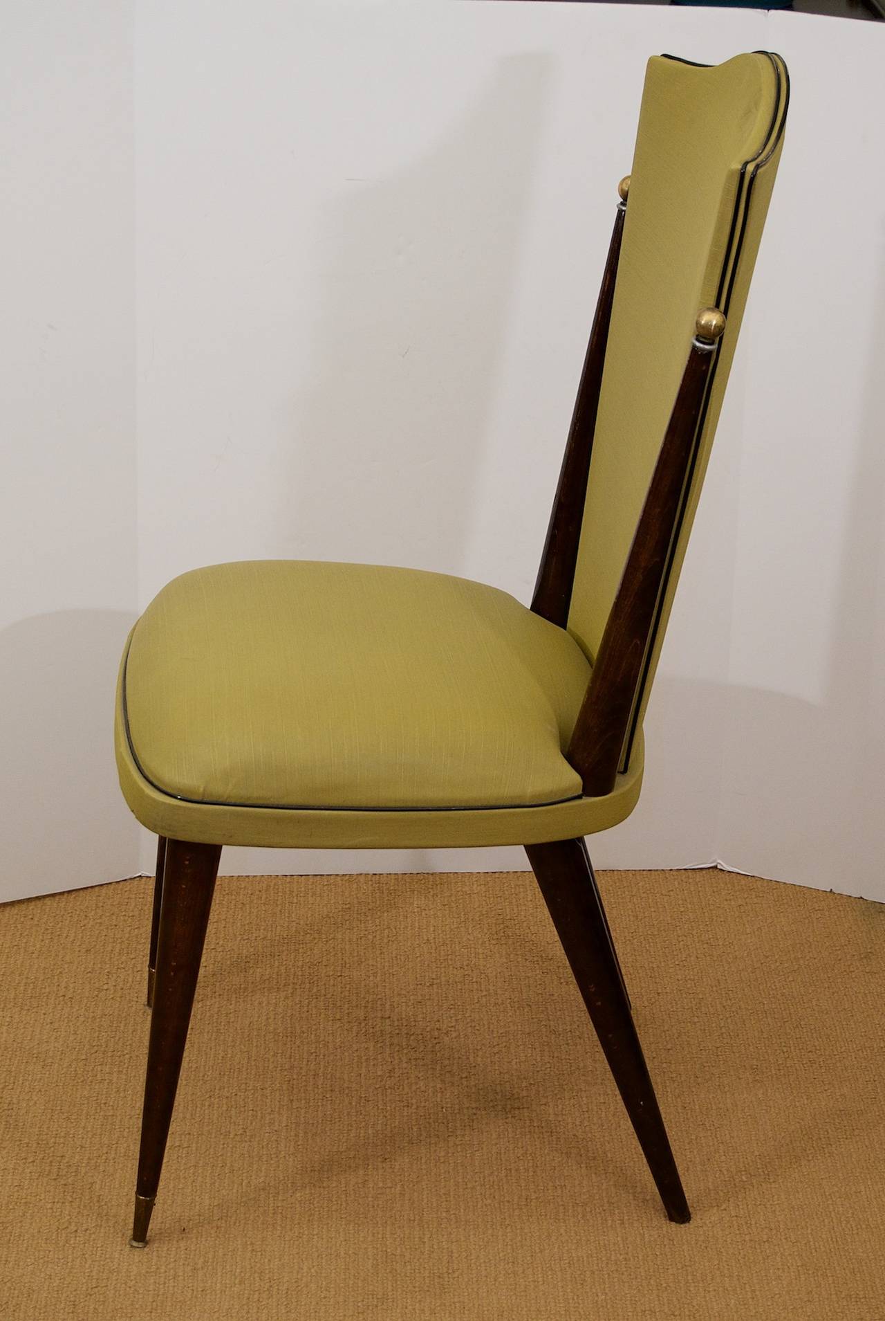 An excellently proportioned set of four dining chairs of Art Deco style. Wood is finished in a satin ebony, with original upholstery.

Turned brass balls at the caps of the back support and sabot on front legs.

Extremely comfortable and
