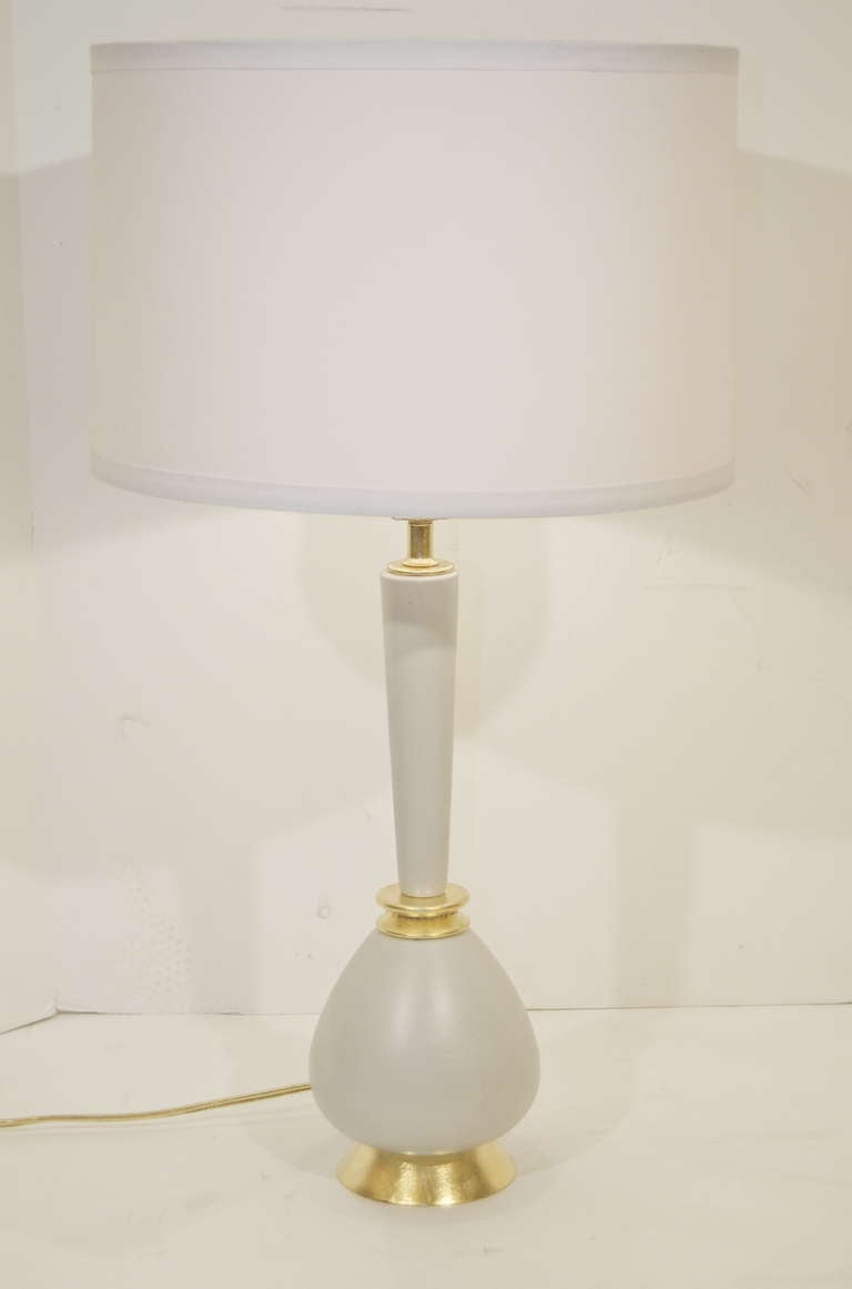 A well-formed pair of gourd-bodied table lamps in a cream ceramic, with gilt wood accents.
Perfect size for bedside or console.
New wiring. Lampshades are for demonstration only and are not included.

Height  is to the finial is 27
