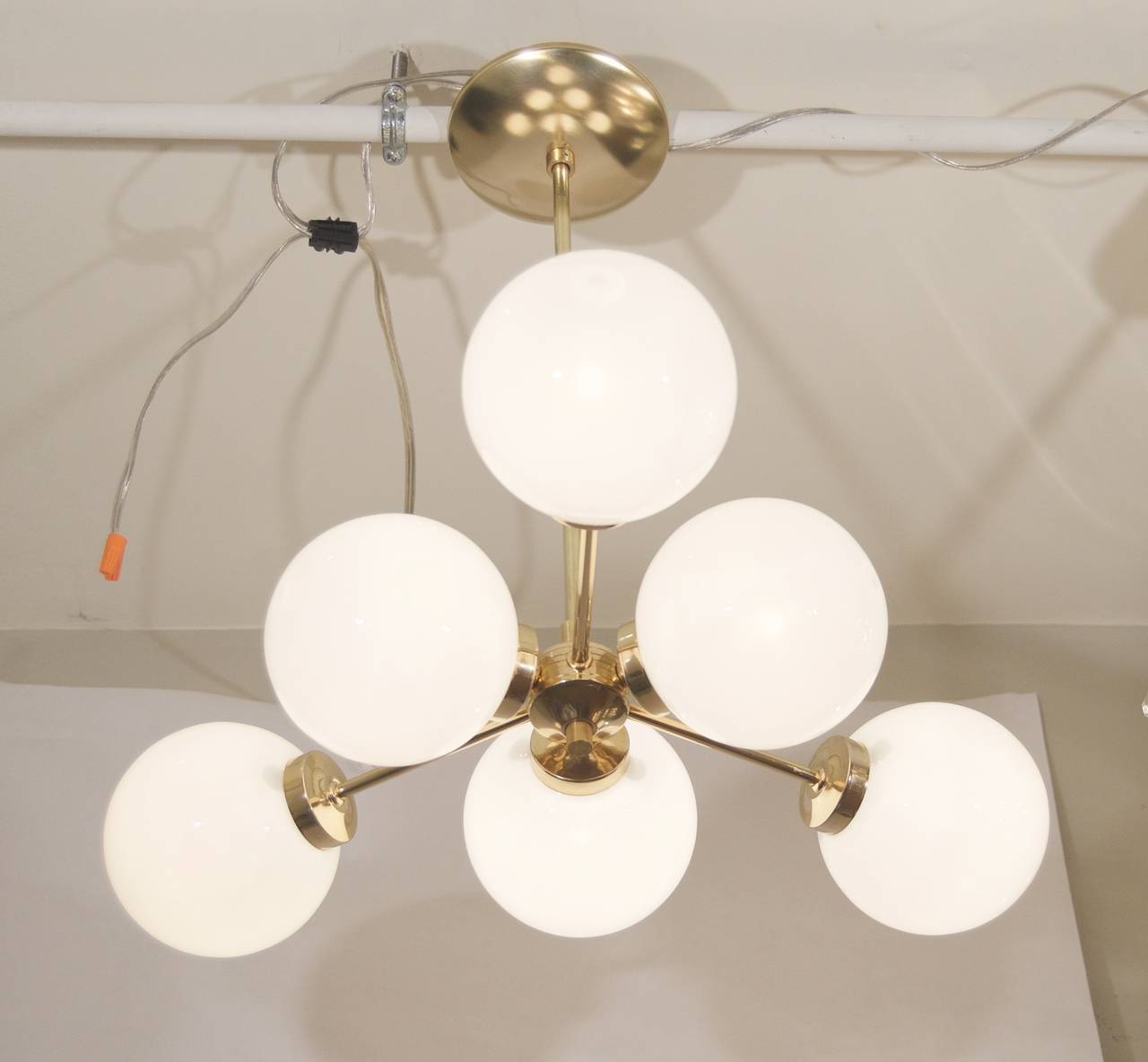 French Sputnik style chandelier in an unusual form, the six gloss opal globes radiating from a central ribbed body to form a triangle. High polish brass body.

New wiring and sockets; takes six E-12 base bulbs up to 40 watts per bulb.

Height