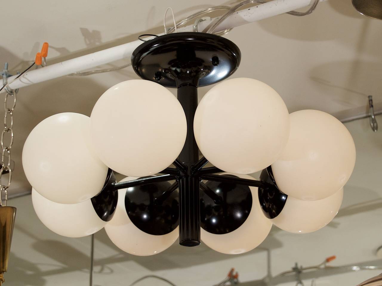 Dramatic radial eight-arm Kaiser chandelier in gloss black with elegant opal glass. 

Takes eight E-14 base bulbs up to 40 watts per bulb. New wiring. Please note height of chandelier is not easily adjusted.