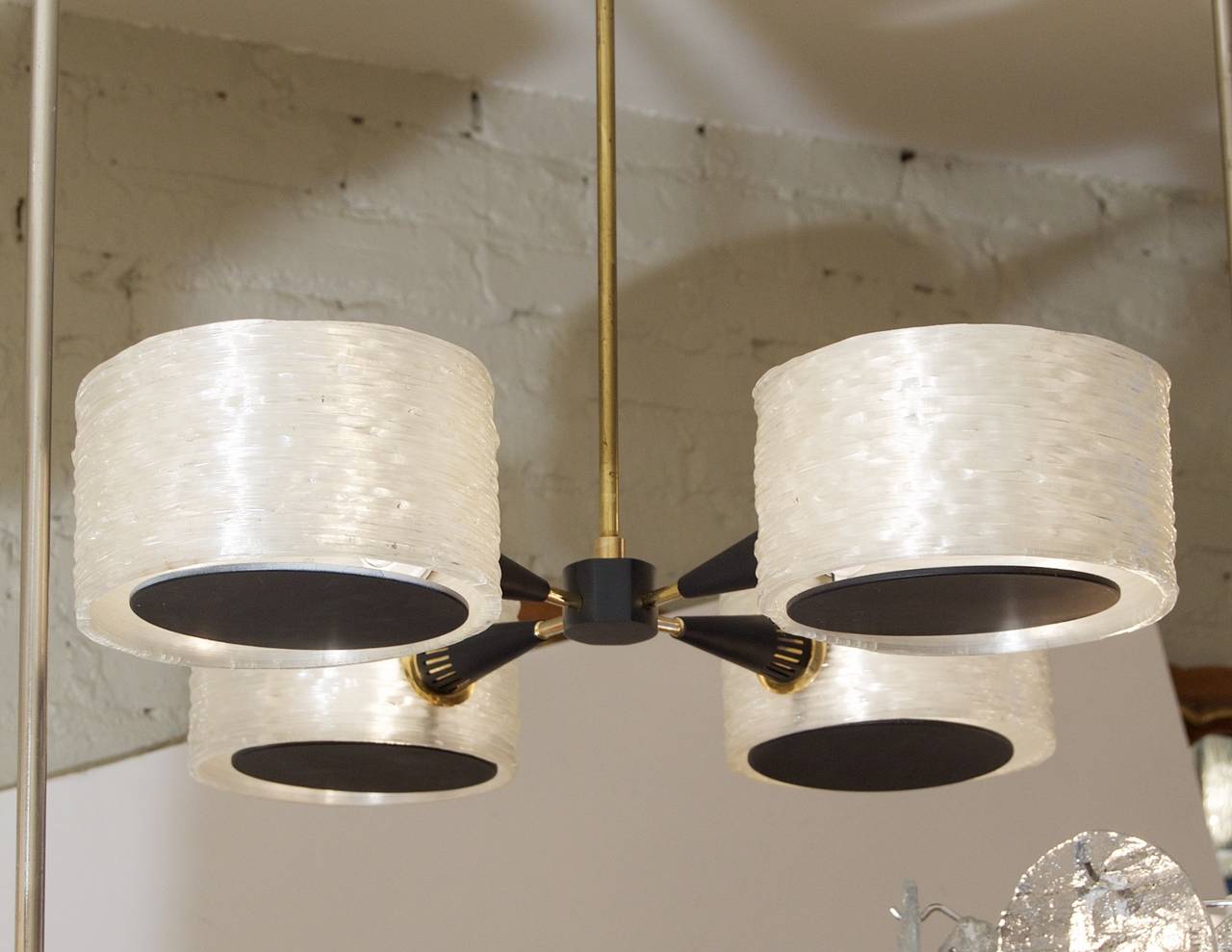 Four brass arms radiating from a central black enameled body each leading to a black enameled cone and spun acrylic cylinder back enameled discs on the bottom of the cylinders.

Takes four candelabra bulbs up to 40 watts per bulb. Height listed is