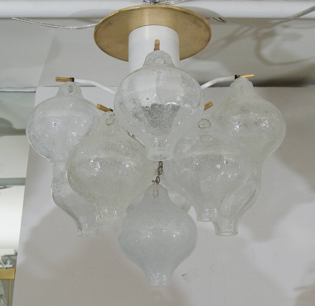 A petite Kalmar Tulipan glass pattern chandelier, having 11 individually hung pieces of glass. Each piece of handblown glass is wire suspended on brass pins, with the central body in enameled white.

Takes one medium base bulb up to 150 watts. New