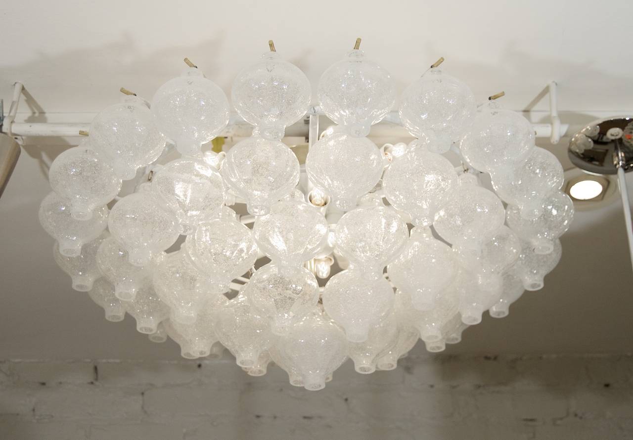 An exceptional Kalmar Tulipan glass pattern chandelier, having 51 individually hung pieces of glass. The outer tier of handblown glass is wire suspended on brass pins and inner tiers hung from hidden hooks, with the central body in enameled white