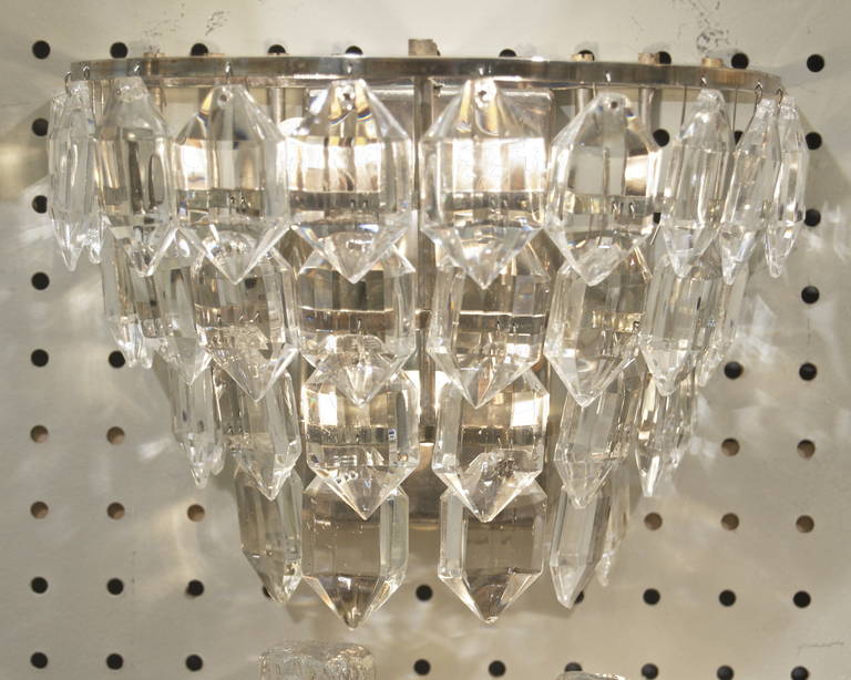 Elegant pair of midcentury sconces. Multiple tiers of crystals in concentric tiers on a silver plated fixture.

Takes three E-14 base bulbs up to 40 watts per bulb, new wiring.

Price listed is per pair. Two pairs available.