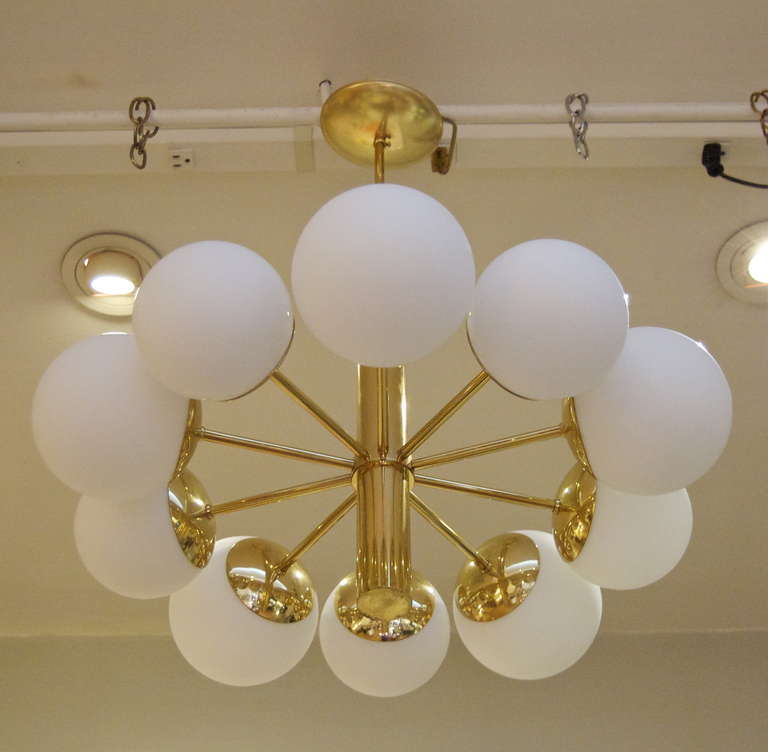 This well proportioned chandelier features ten opal glass globes radiating from a central brass cylindrical body. Elegant look for many situations. Five larger and smaller globes each alternating around the perimeter of the chandelier create