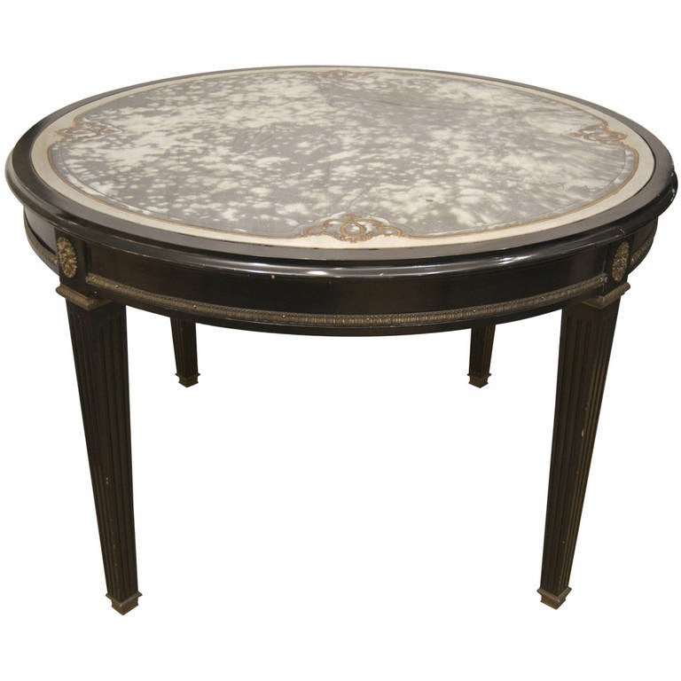 Fantastic large center table in black lacquer with bronze ornamentation, the top having inset églomisé glass top. Smoked center with silver border, separated by etched and gilt scrollwork.

Height would work well as dining table.

Stamped Jansen on