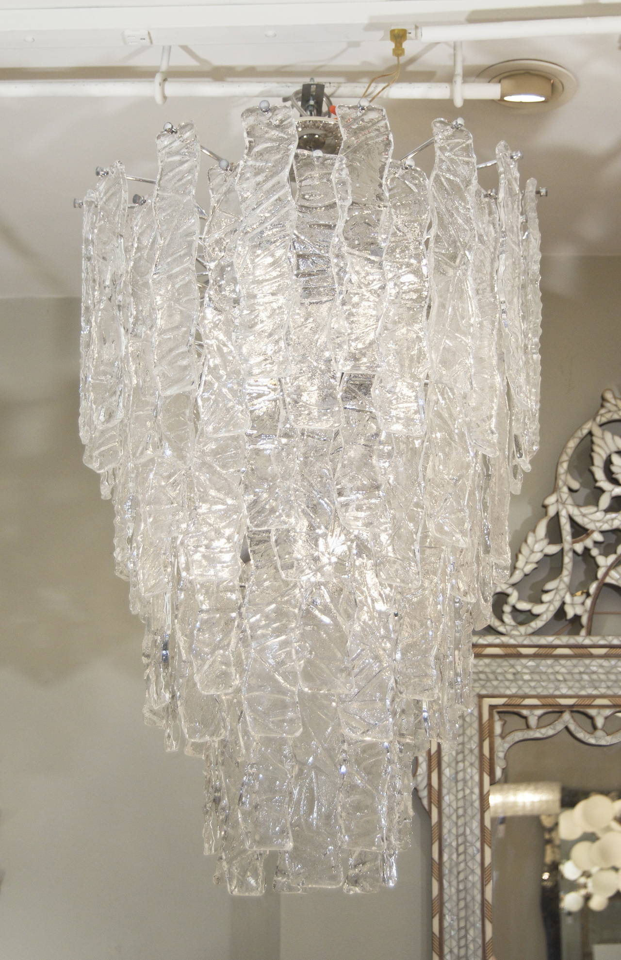 Fantastic Murano glass chandeliers possibly by Mazzega comprised of eight staggered tiers of vertical zig-zag glass with an ice crackle surface each piece 11" long, retained with chrome hardware. A grand scale and dramatic statement for any